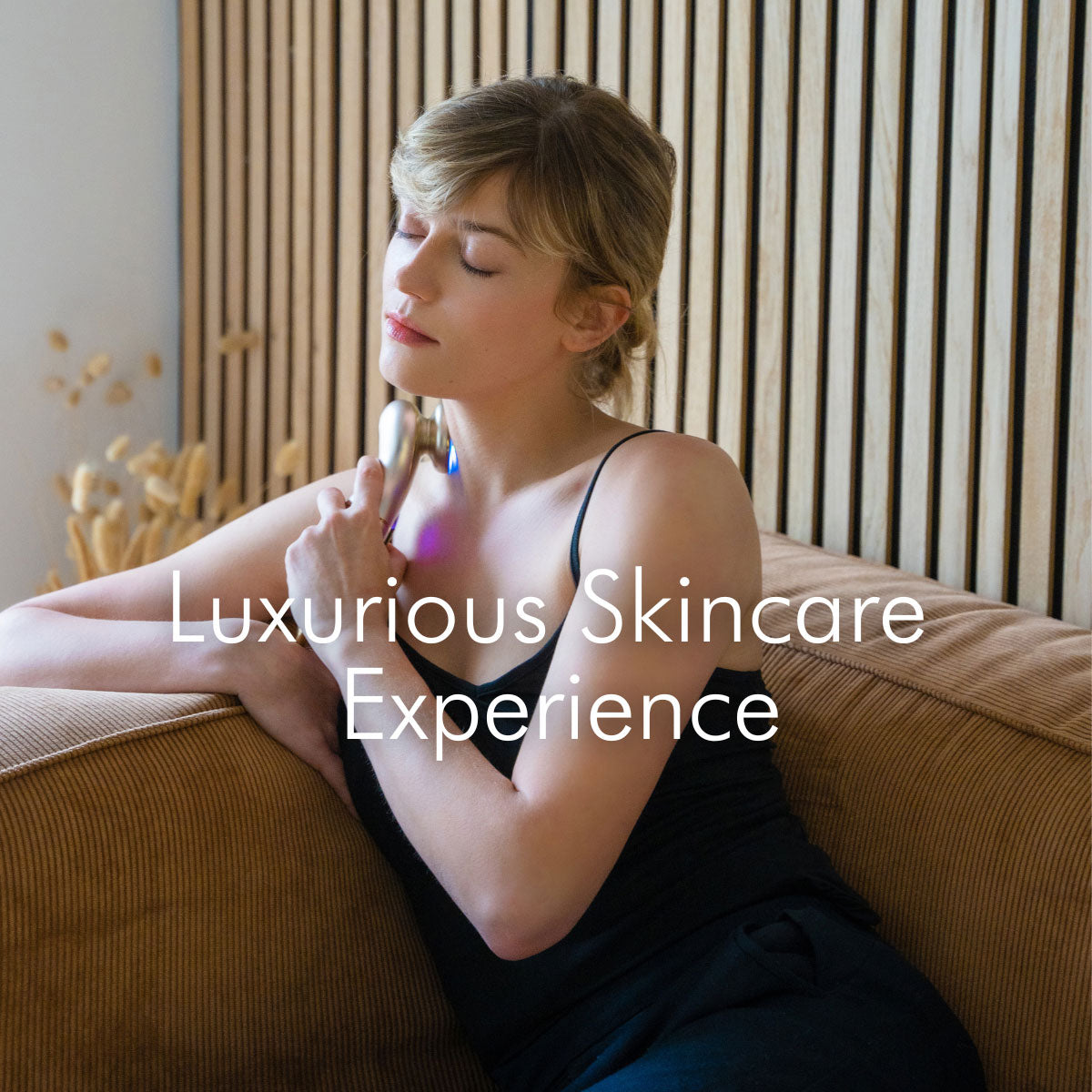 European woman with relaxed expression using CHOUCHOU TOKYO The Morpho on a sofa, eyes closed, word 'Luxury Skincare Experience' displayed over the image.